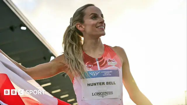 Georgia Hunter Bell smiles while unfurling an England flag