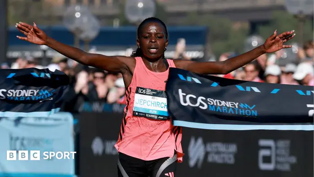 Peres Jepchirchir in a pink top with arms outstretched, breaking a ribbon as she crosses the finish line at the Sydney marathon